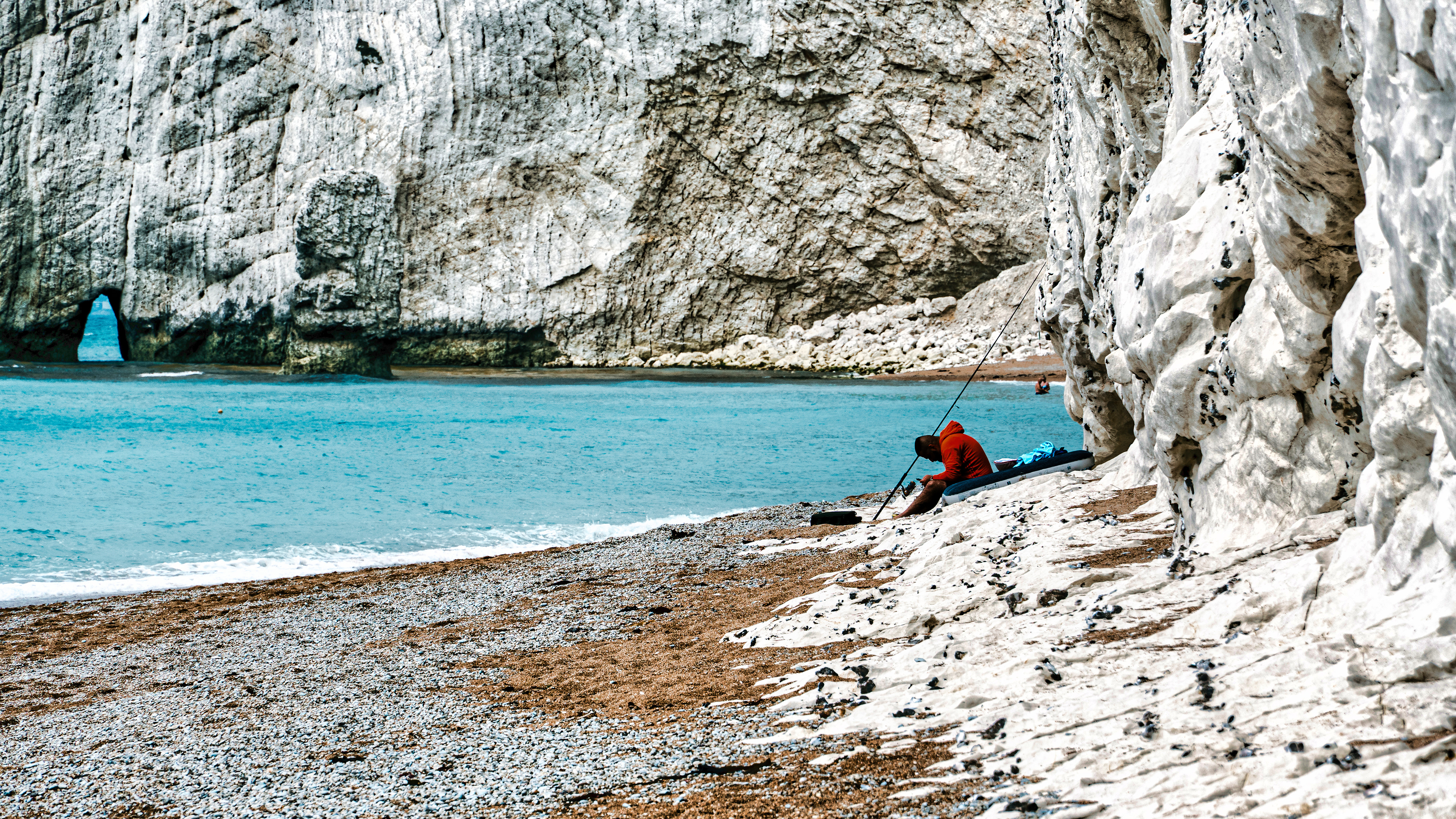 Sitting by the sea, surrounded by tall white cliffs.