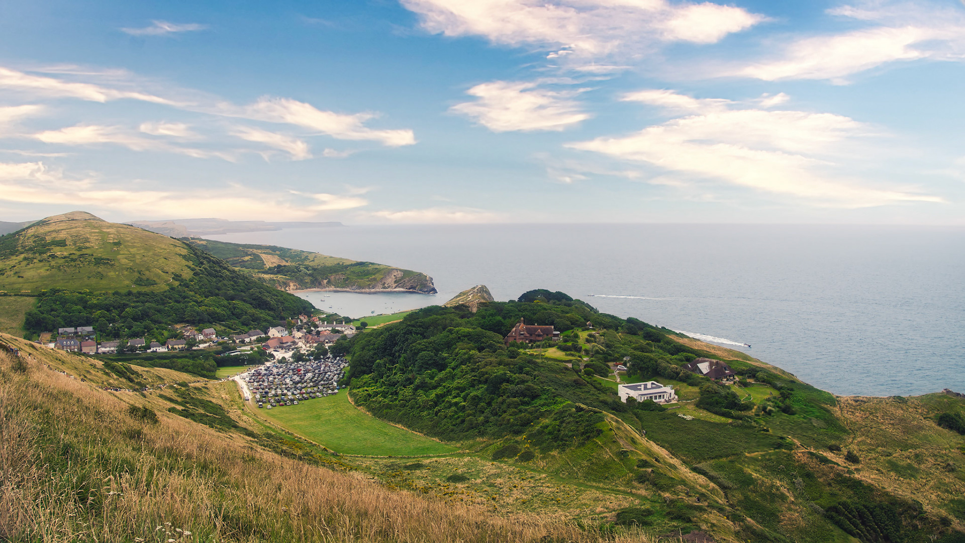 A scenic view over Lulworth Cove, where rolling hills meet the calm sea.