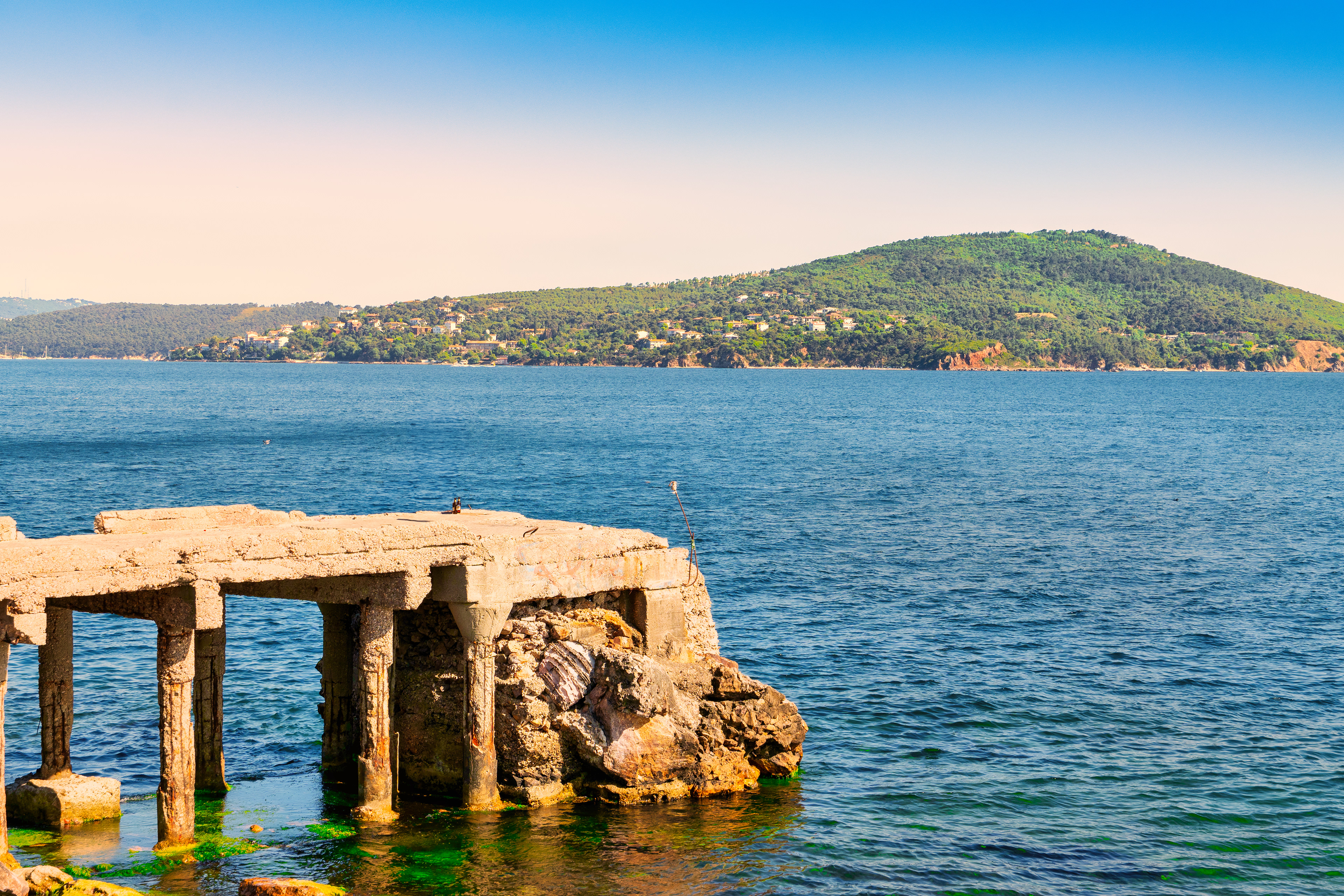 Old pier, calm sea, and a hill watching from afar.