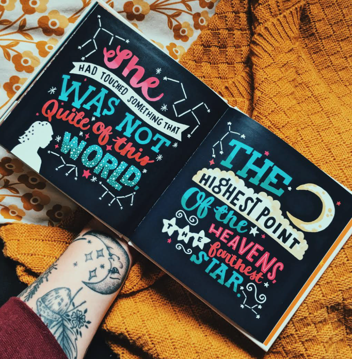 the photo shows a double page spread of a book. the background is a dark navy blue and the text is a mixture of text styles in pink, blue and cream. The text reads "she had touched something that was not quite of this world, the highest point of the heavens, the farthest star" 