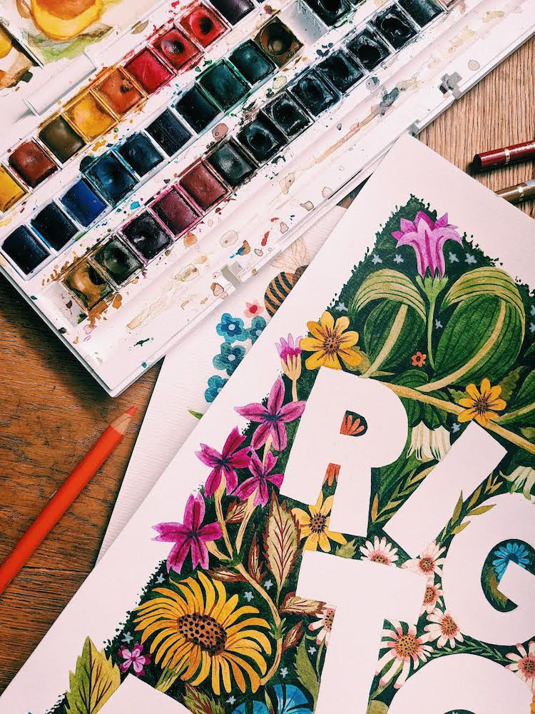 An image of a watercolour painting. The text on the painting reads Right to Roam. The text is surrounded by brightly coloured flowers and plants that have been painted using watercolour paints.