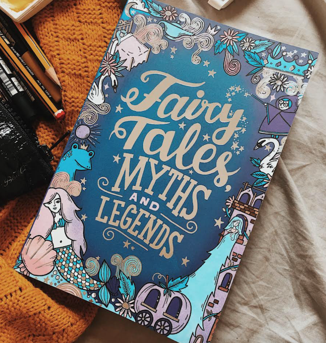 the photo shows a book cover which title is "fairy tales, myths and legends" It's blue, purple and silver in colour and features a border of fairy tale characters with flowers and stars