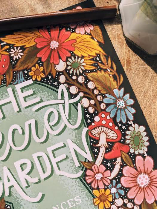 the image shows a cover of the book "the secret garden" by Frances Hodgson Burnett. The text is written inside  an illustration of a keyhole which is surrounded by flowers, fruits and leaves. A close up.