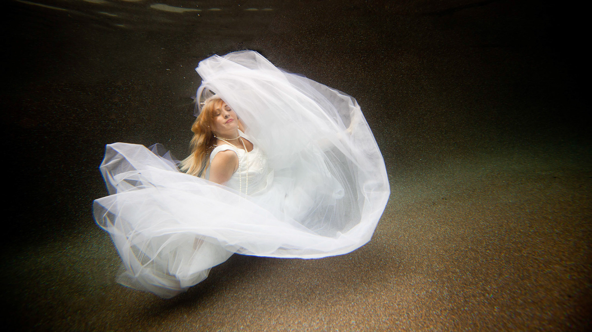 8815-Bridal art trash the dress style.Helen in her wedding dress taking the plunge. We took these images in Helen's pool, love the dark finish. In all of these images both the model and photographer are underwater.
