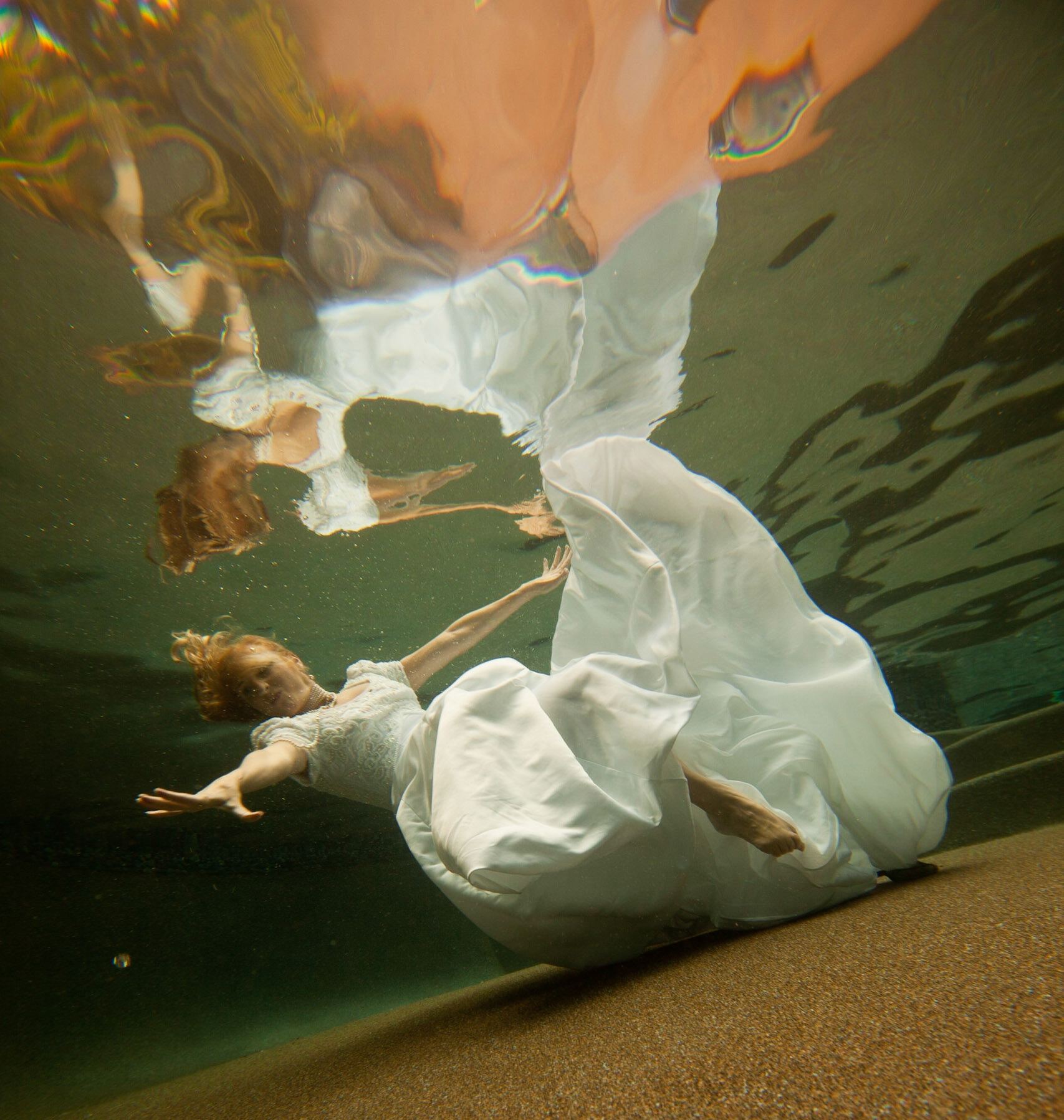 8017-Bridal art trash the dress style.Helen in her wedding dress taking the plunge. We took these images in Helen's pool, love the dark finish. In all of these images both the model and photographer are underwater.