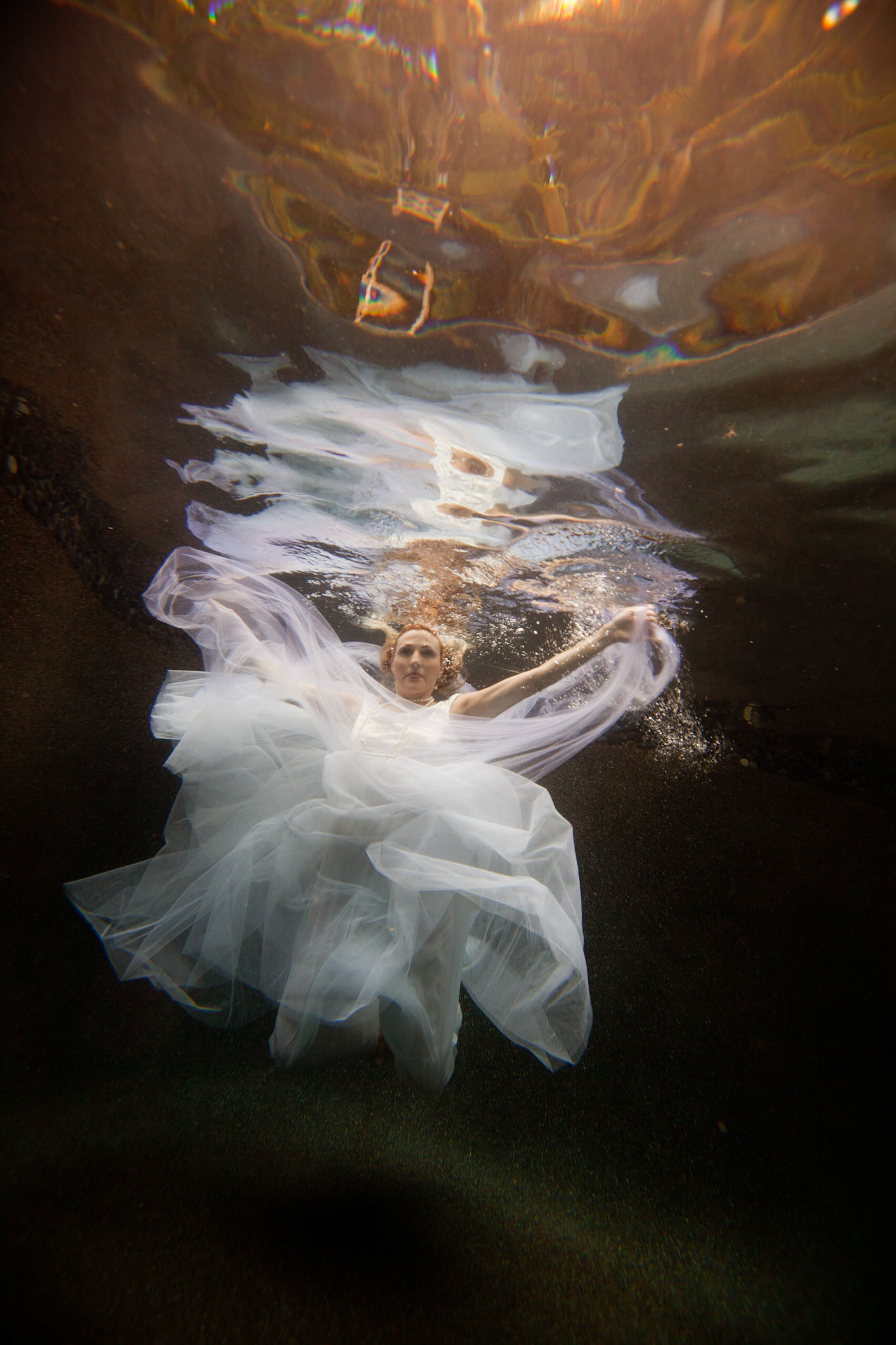 8815-Bridal art trash the dress style.Helen in her wedding dress taking the plunge. We took these images in Helen's pool, love the dark finish. In all of these images both the model and photographer are underwater.