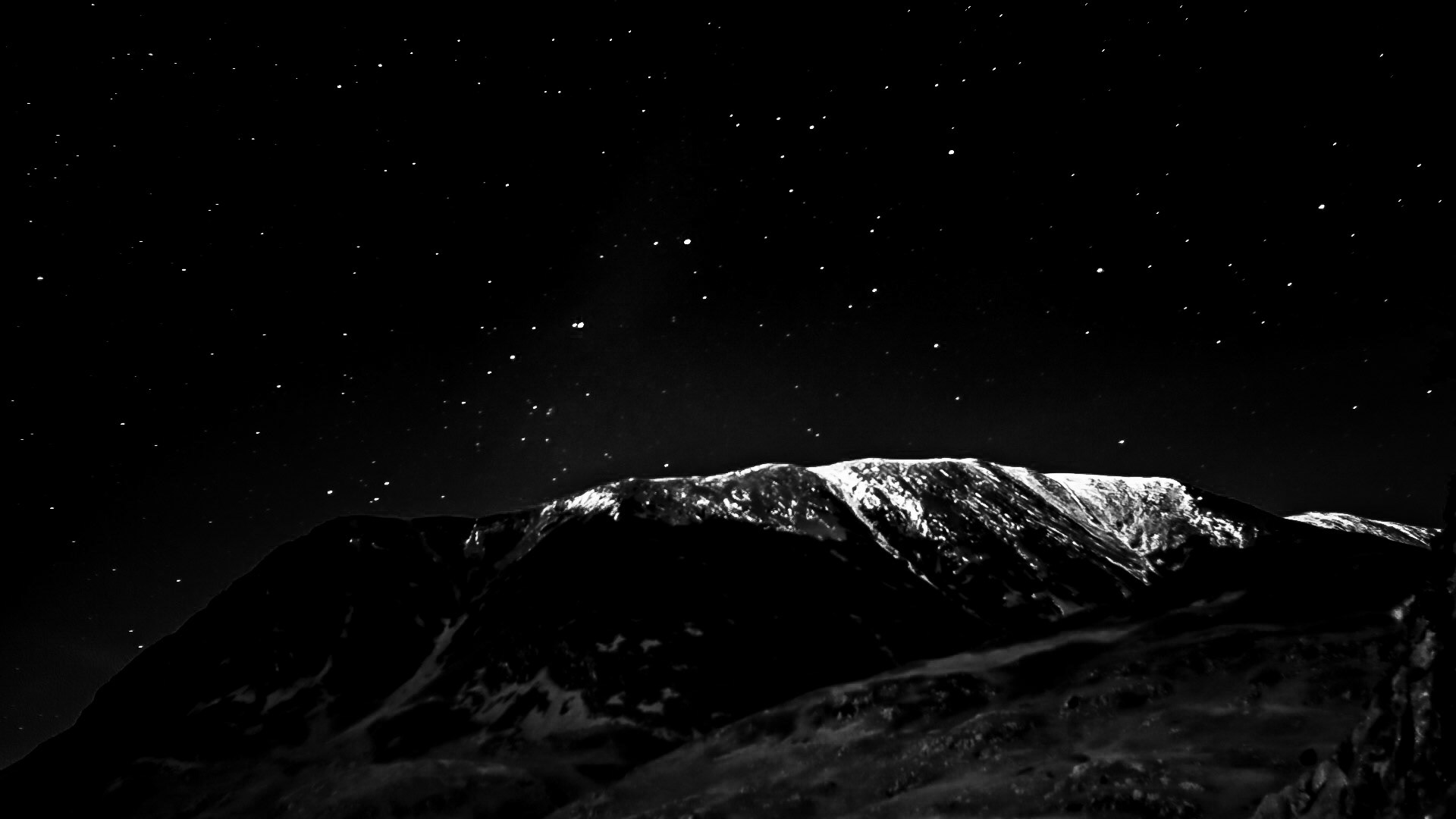 Monochrome snow covered mountain top with space and stars as the backdrop.