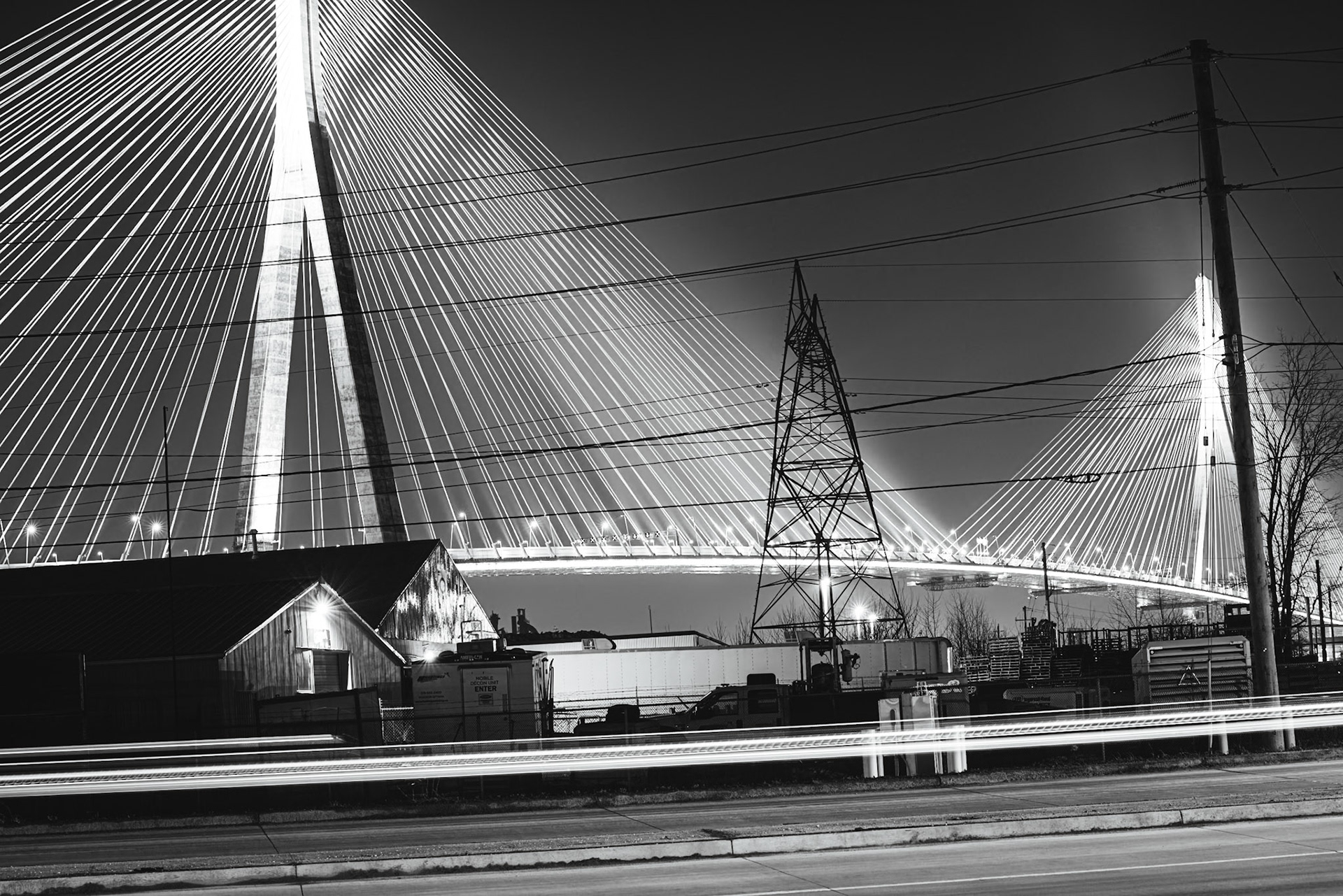 Monolithic Noir study of the Gordie Howe International Bridge, rendered with maximum depth of field to include foreground industrial grit. A.M. Stone | Archival Stone Photography