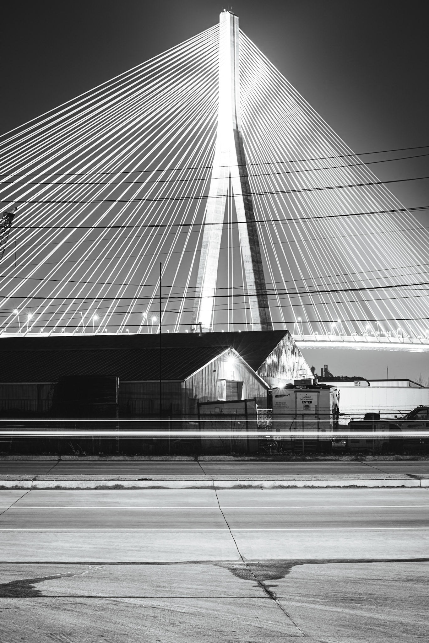 Monolithic Noir study of the Gordie Howe International Bridge, rendered with maximum depth of field to include foreground industrial grit. A.M. Stone | Archival Stone Photography