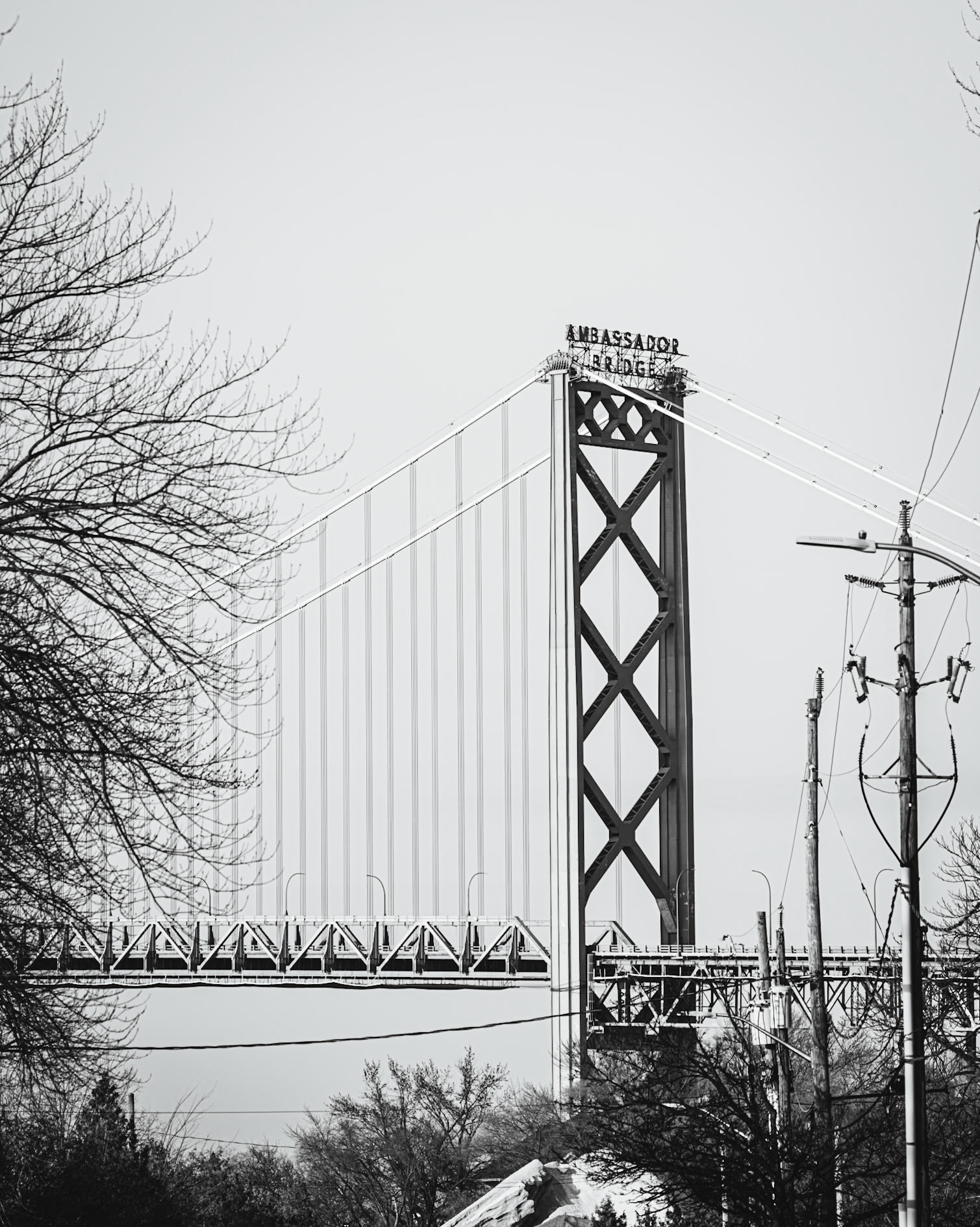Monolithic Noir study of the Ambassador International Bridge, rendered with maximum depth of field to include foreground industrial grit. A.M. Stone | Archival Stone Photography