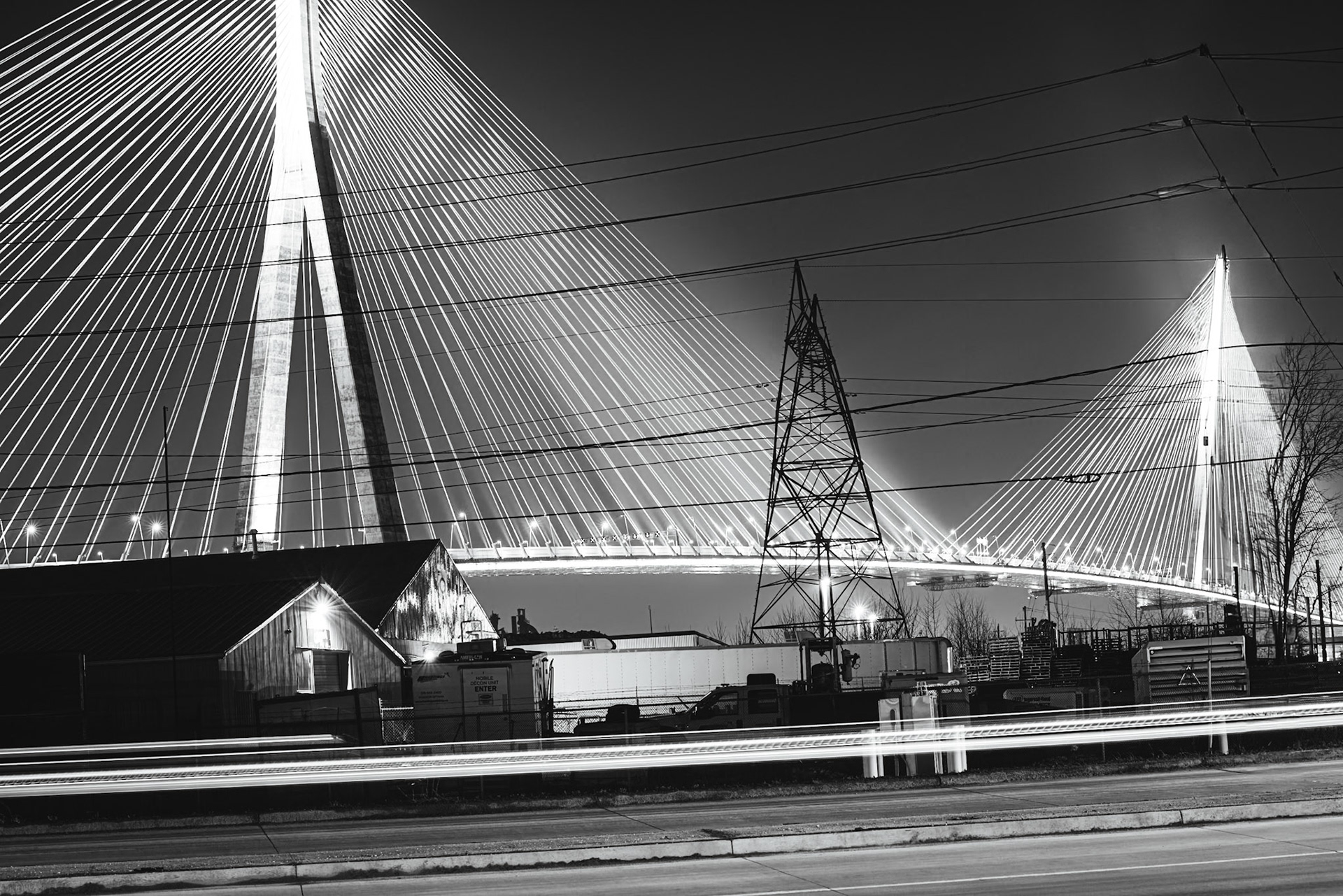 Monolithic Noir study of the Gordie Howe International Bridge, rendered with maximum depth of field to include foreground industrial grit. A.M. Stone | Archival Stone Photography