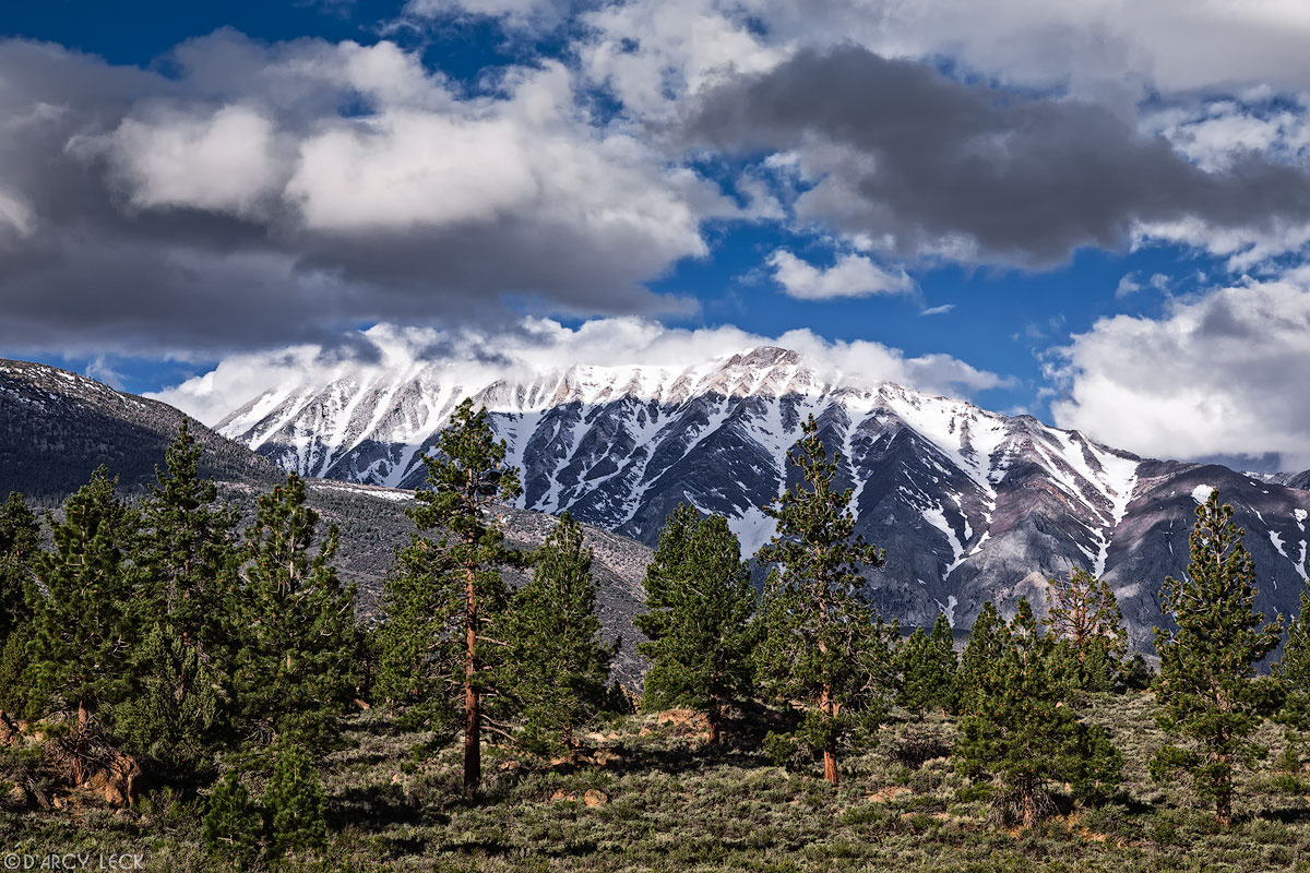 Clearing storm clouds enshroud tops of peaks of Sierra Nevada Mountains in John Muir Wilderness at sunrise, California