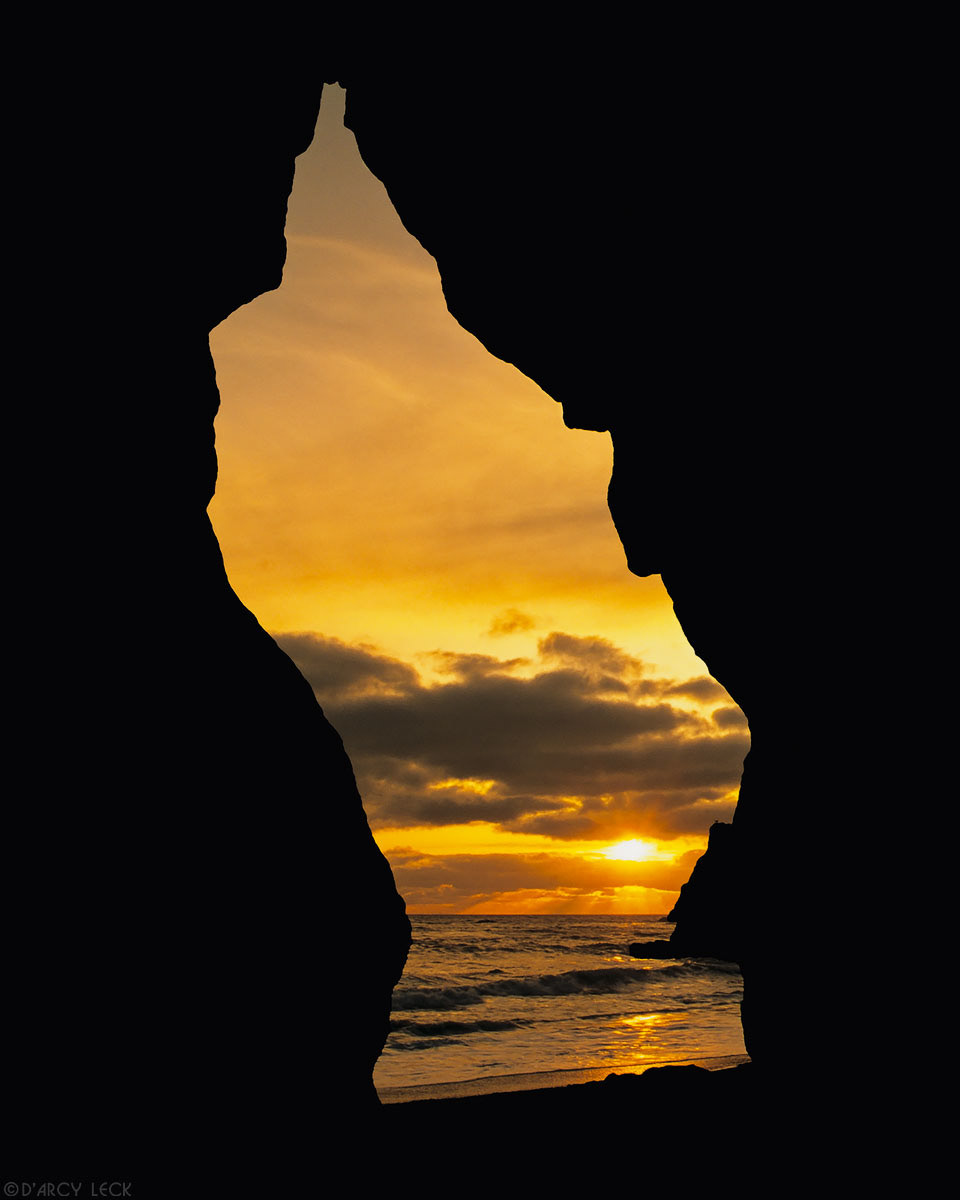 Sunset over Pacific Ocean seen through hole in rock along Ruby Beach, Washington