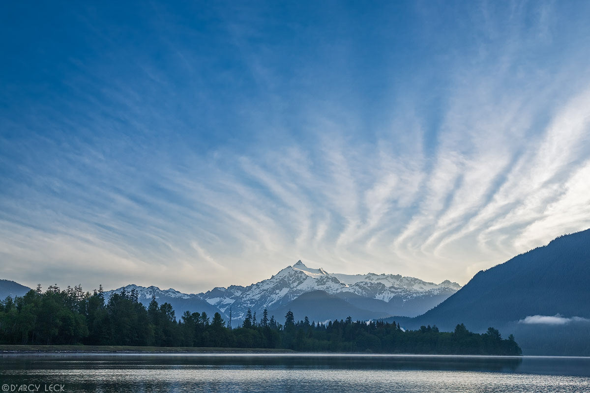 Mount Shuksan and cirrus clouds catch morning sunrise light and reflect in Baker Lake, Washington