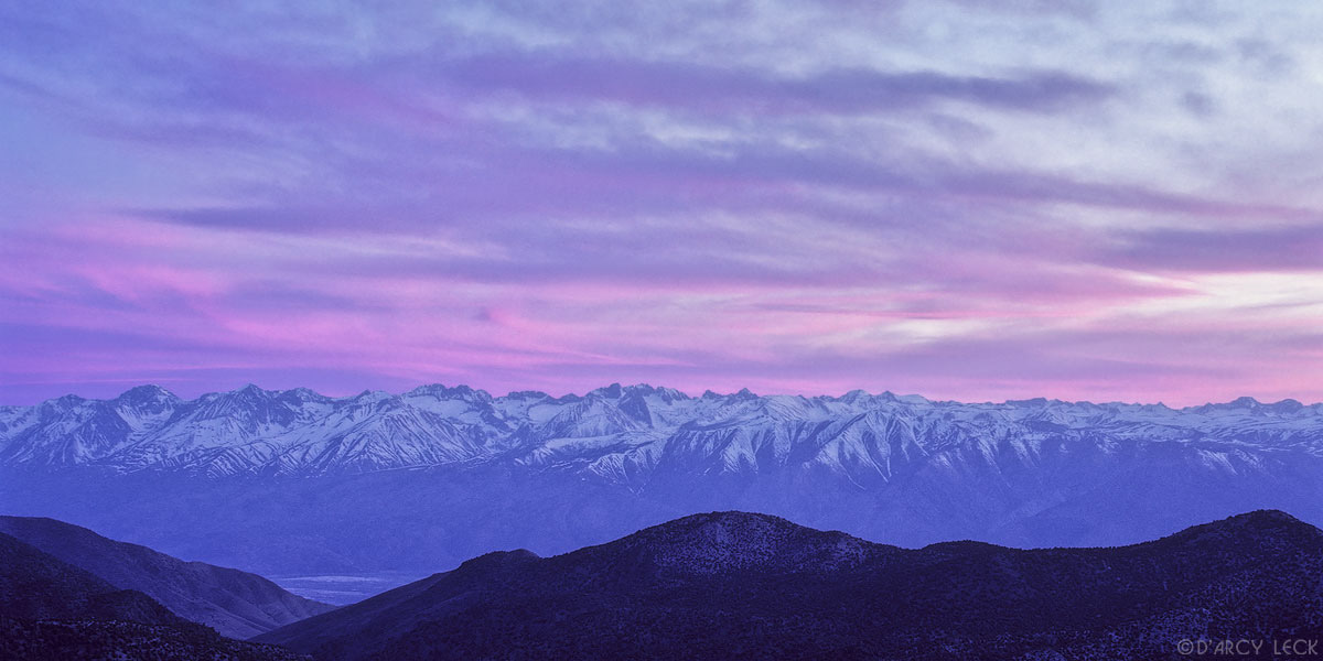 Clouds glow magenta at dusk over the snow capped Sierra Nevada Mountains, Califronia