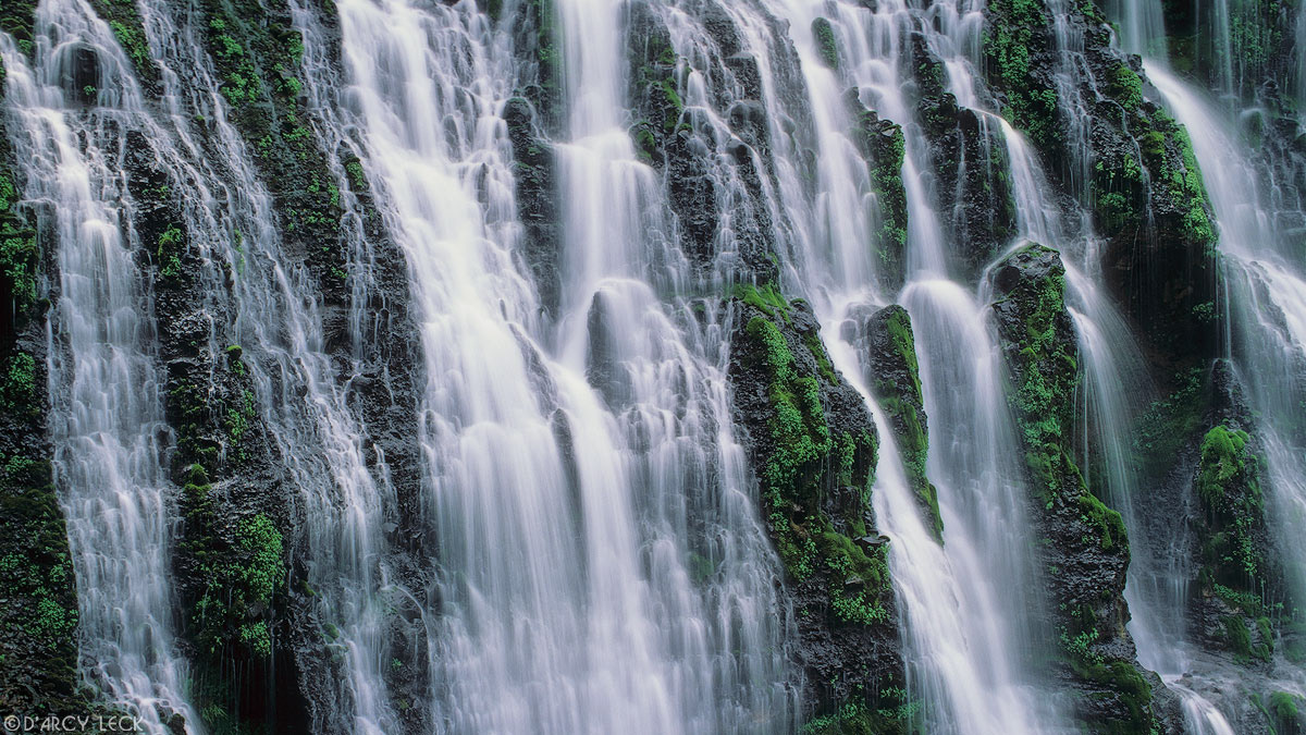 Water of Burney Falls streams down a verdant cliff at McArthur-Burney Falls Memorial Park, California