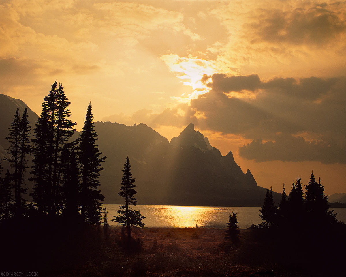 Sun rays beam from behind clouds in late afternoon over The Ramparts and Amethyst Lake. Canadian Rockies, Canada