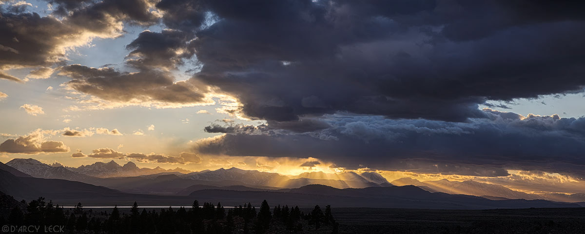 Sun rays beam through clouds at sunset over the Ritter Range of the Sierra Nevada Mountains near Mammoth Lakes, California