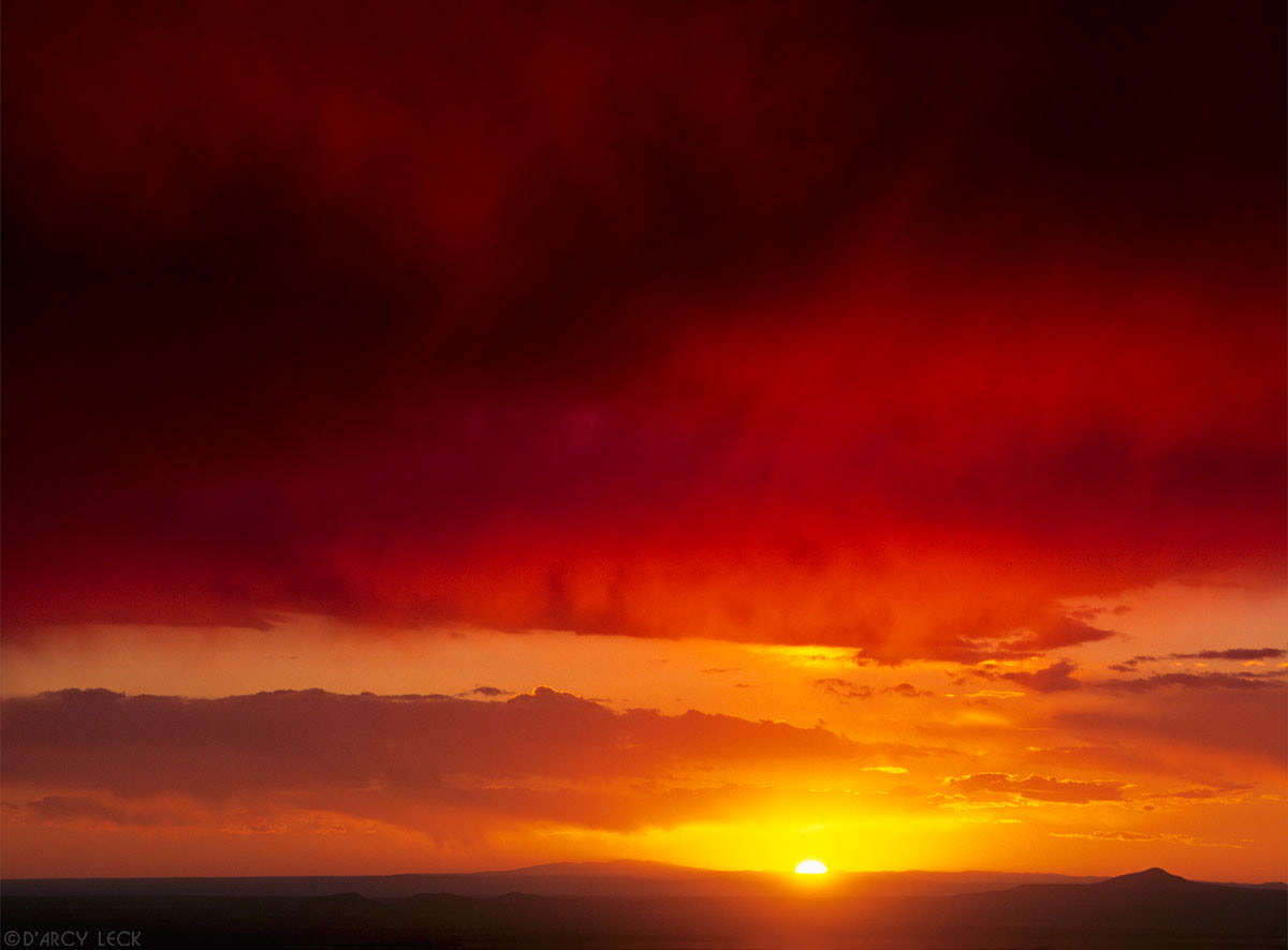 Virga falls from sky as the sun sinks behind the Jemez mountains, New Mexico