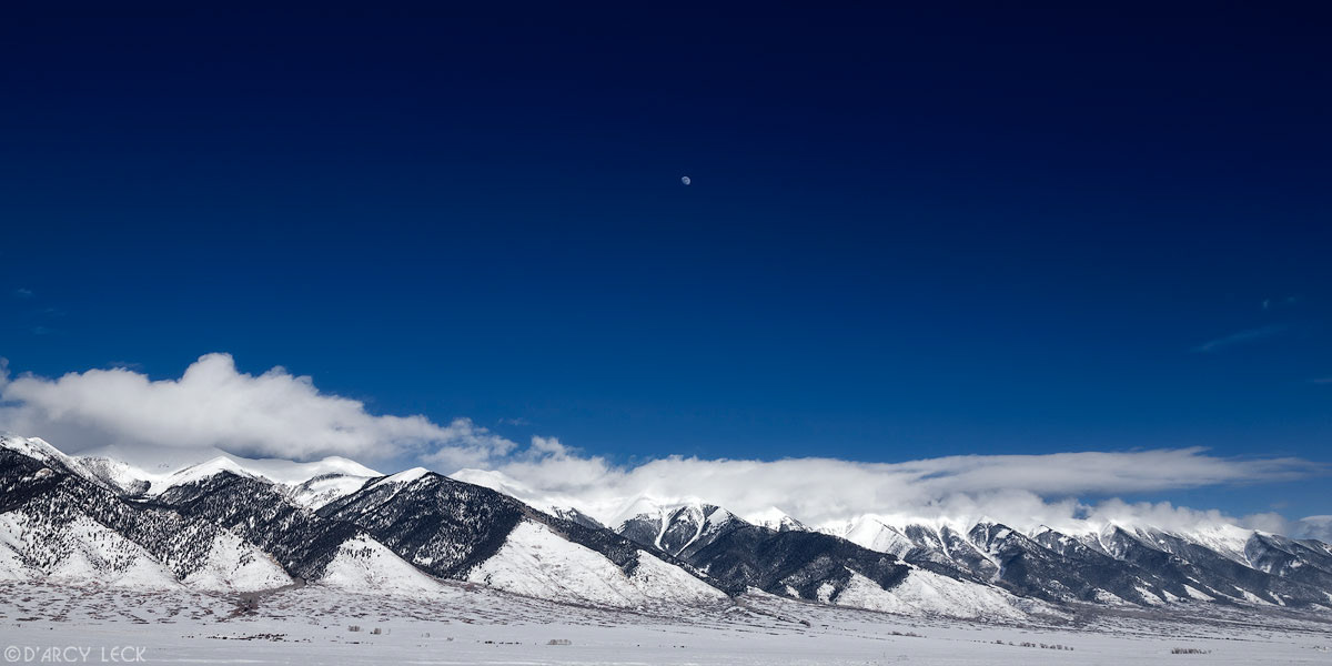 A near full moon in sky above Sangre de Cristo Mountains after winter storm, San Luis Valley, Colorado