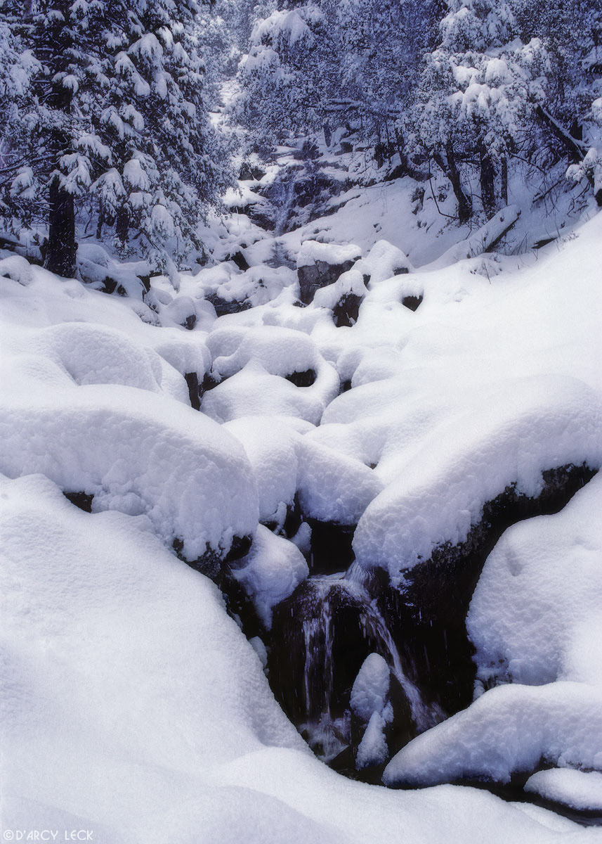 New snow covers rocks along creek in Sierra Nevada Mountains California