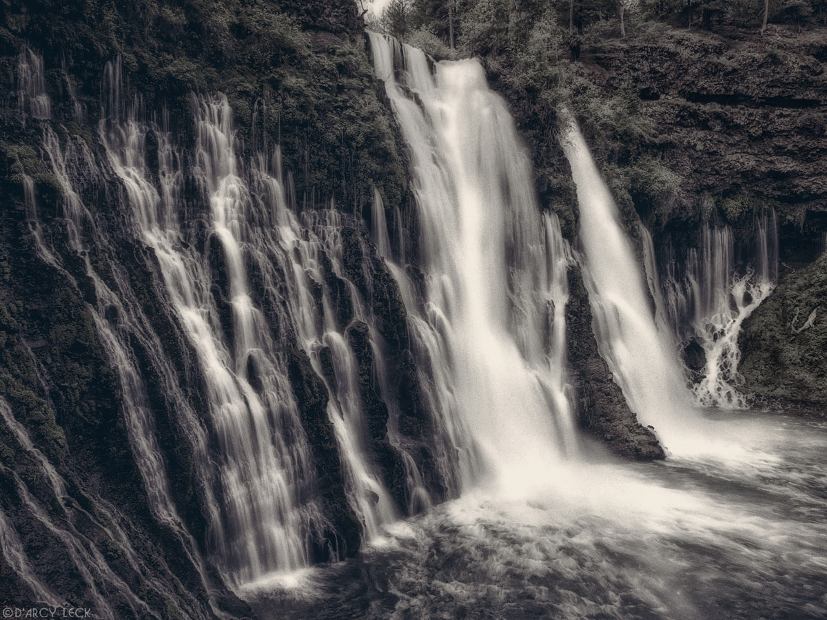 Water of Burney Falls streams down a verdant cliff at McArthur-Burney Falls Memorial Park, California
