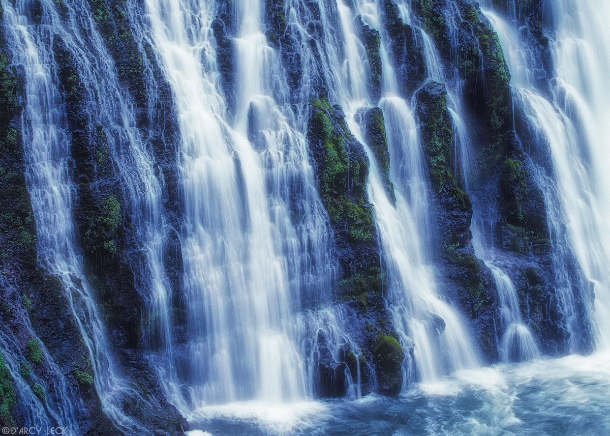 Water of Burney Falls streams down a verdant cliff at McArthur-Burney Falls Memorial Park, California