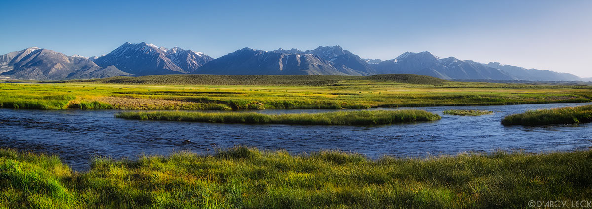 Owens River flows through wetland above Crowley Lake in late afternoon with the Sierra Nevada Mountains in distance, California