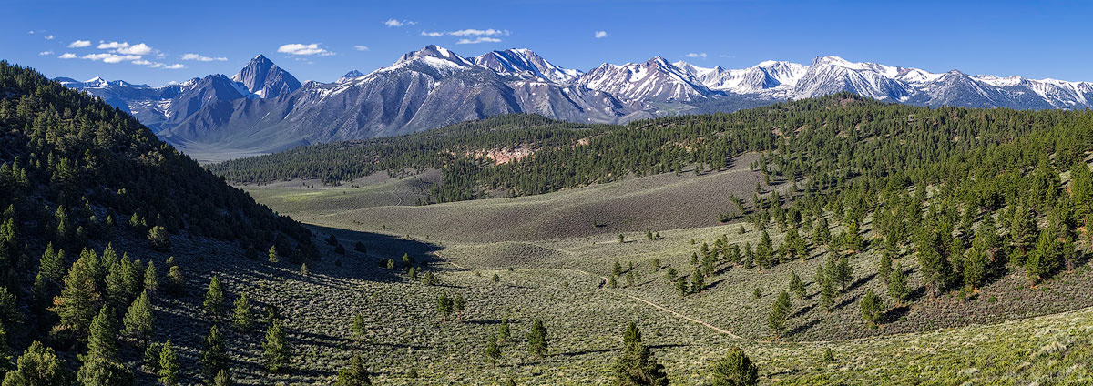 Sierra Nevada Mountains in the John Muir Wilderness rise in the distance beyond forested hills and valleys of Smokey Bear Flat, California