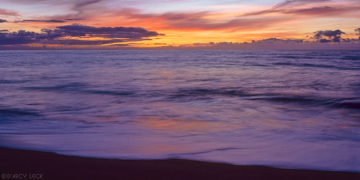 Sunset over Pacific Ocean and surf on beach, Polihale State Park, Kauai, Hawaii