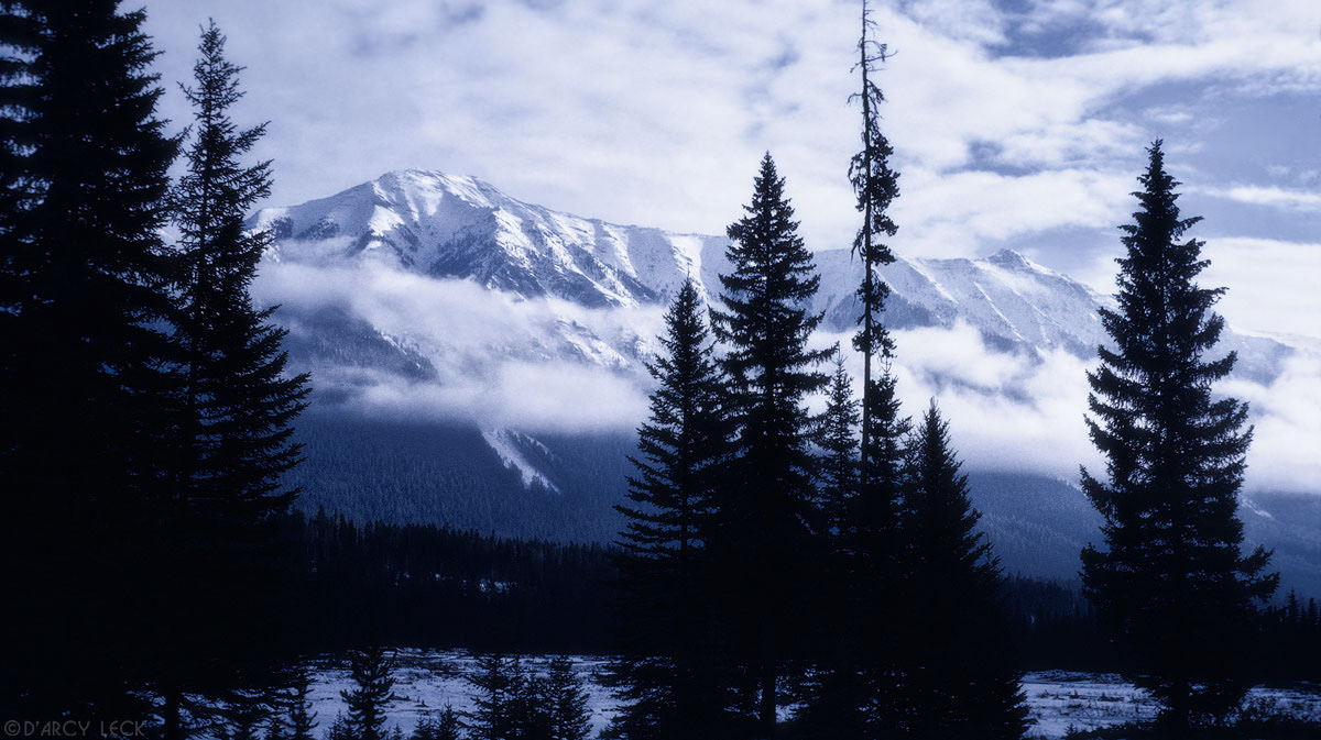 Clearing clouds from snow covered Rocky Mountains in winter, British Columbia, Canada