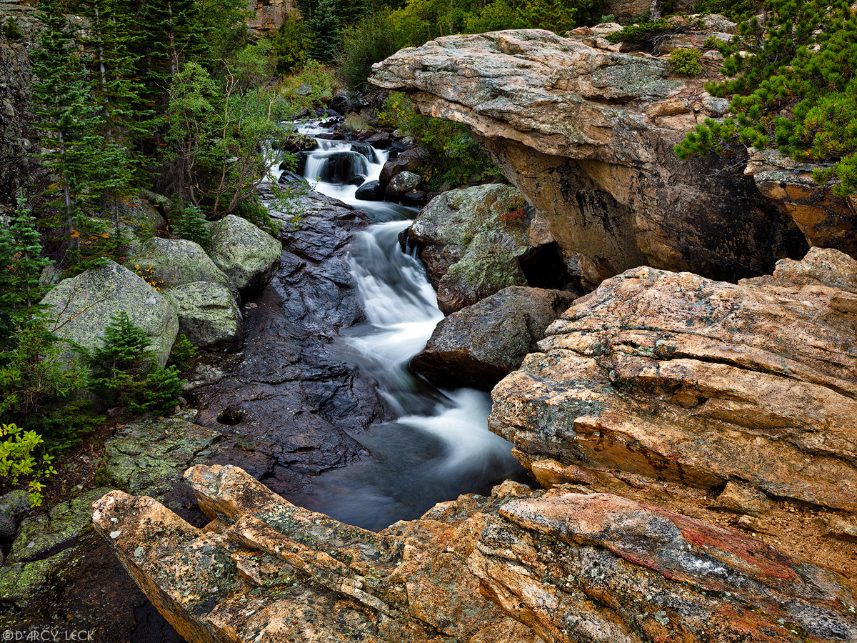 Rock ledges over hang cascading waters of Glacier Creek, Colorado
