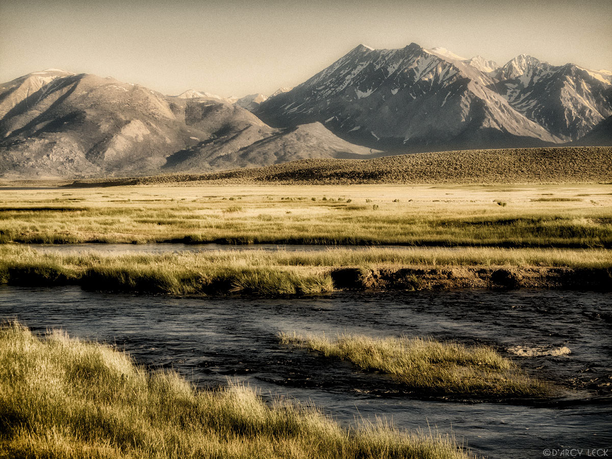 Owens River flows through wetland above Crowley Lake in late afternoon with the Sierra Nevada Mountains in distance, California