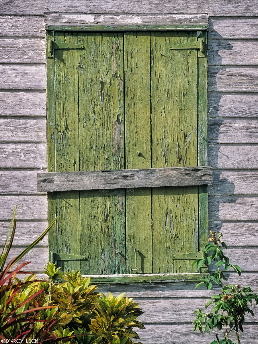 Old weathered green window on side of house in New Plymouth, Bahamas