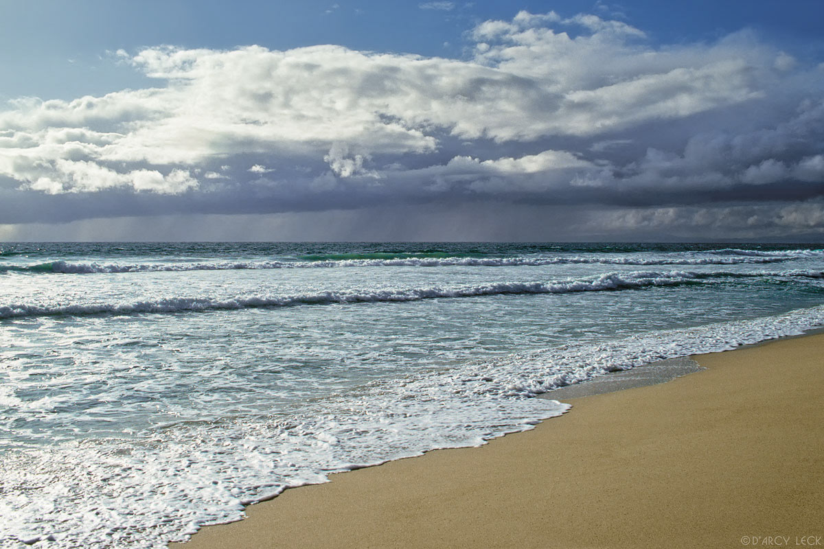 Surf on beach with rain streaming from storm clouds over Pacific Ocean, Monterey Bay, California