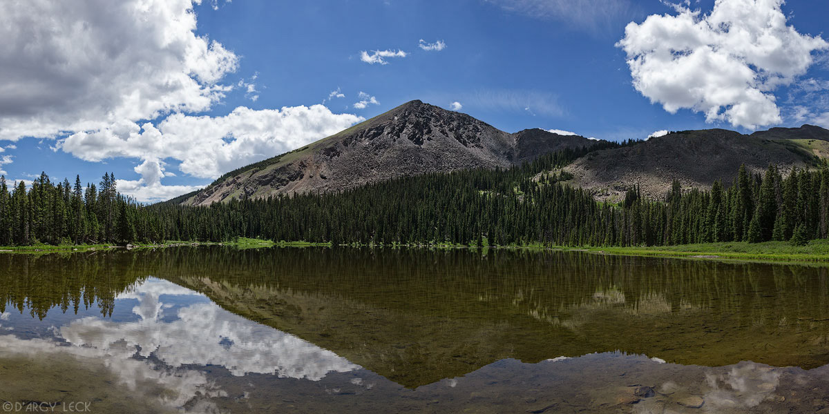 Mountain reflects in forest lined Hartenstein Lake on a summer day, Colorado