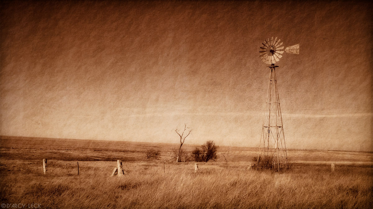 Windmill and Rock post fence on plains in December near Russell, Kansas