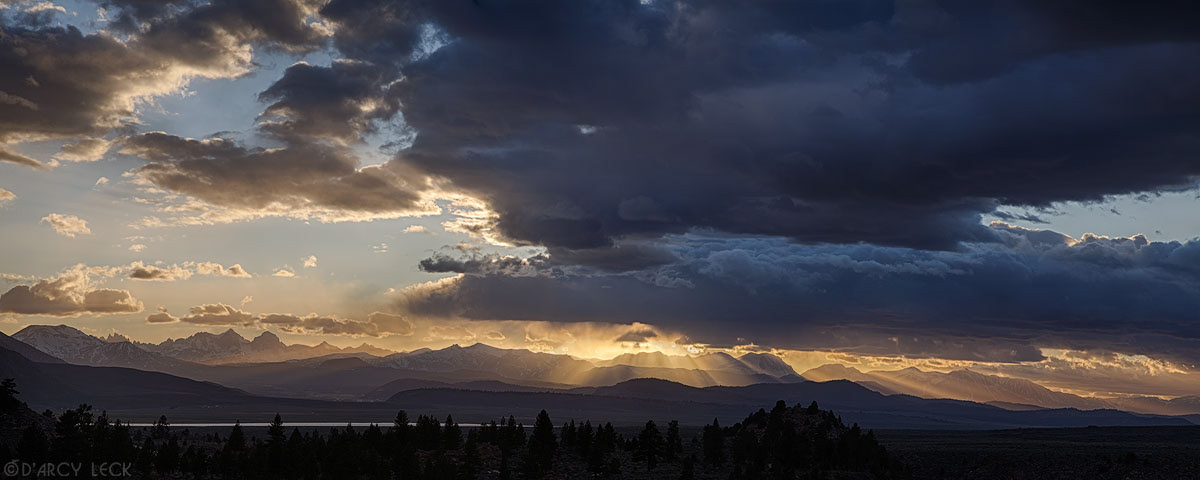 Sun rays beam through clouds at sunset over the Ritter Range of the Sierra Nevada Mountains near Mammoth Lakes, California