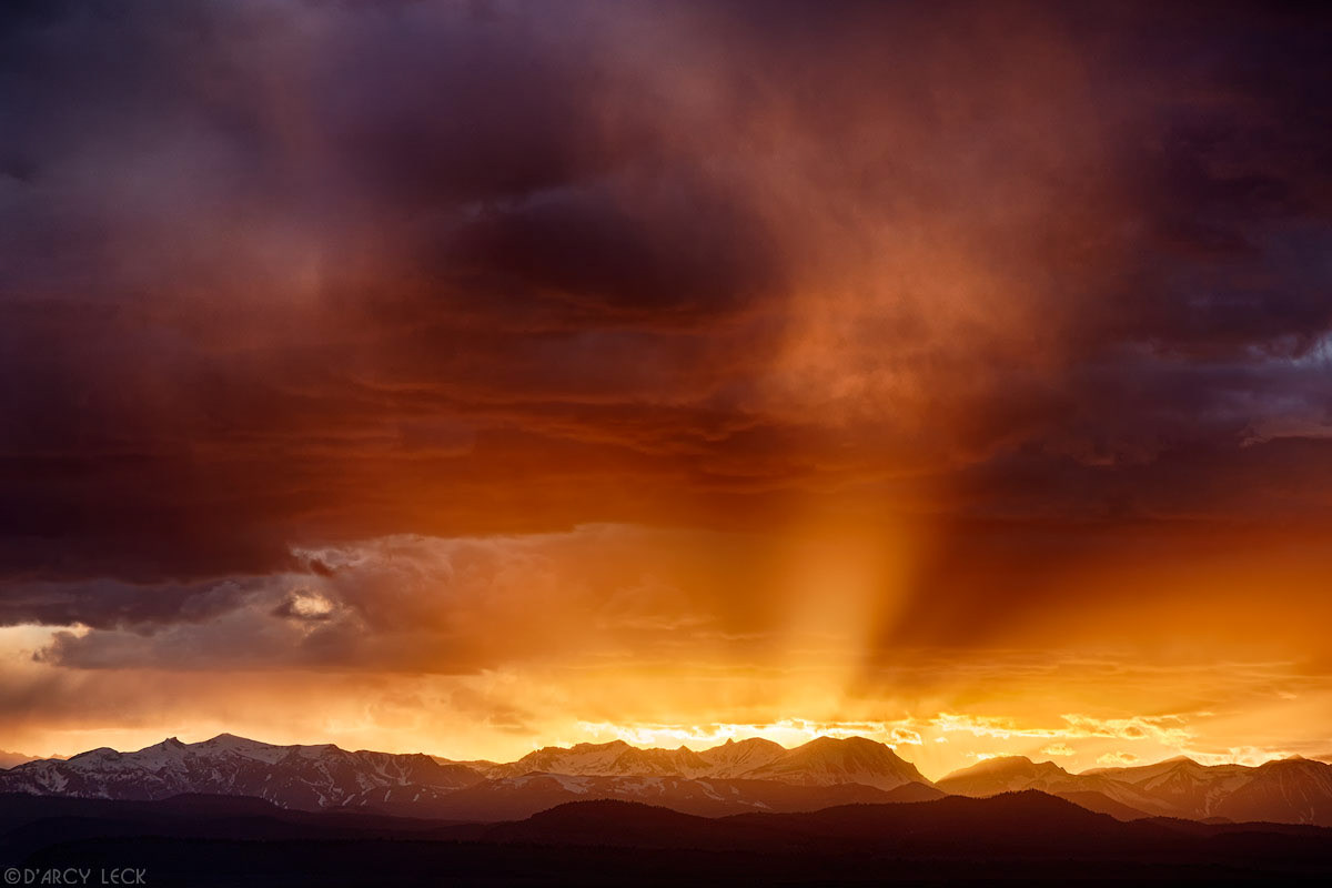 Sun rays beam through clouds at sunset over the Ritter Range of the Sierra Nevada Mountains near Mammoth Lakes California