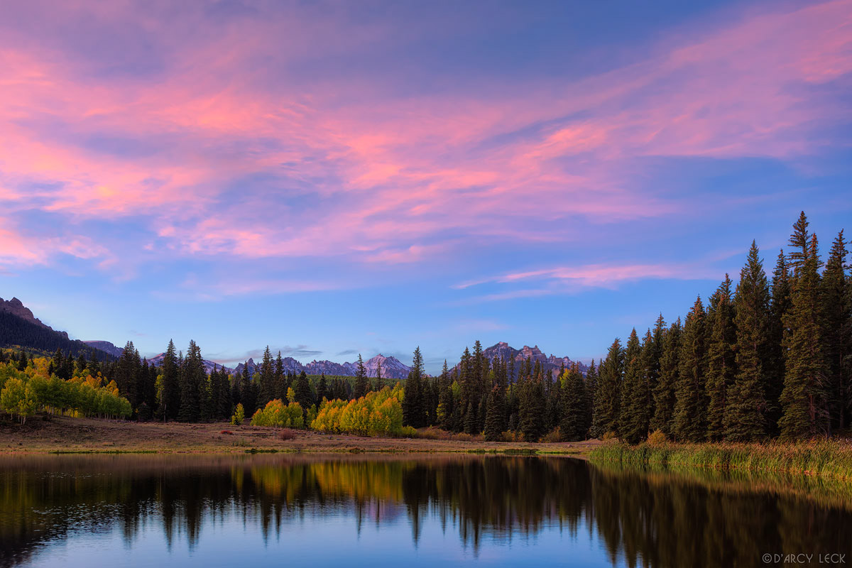 San Juan Mountains and forest in early Autumn colors reflect in Beaver Lake at dawn, Colorado