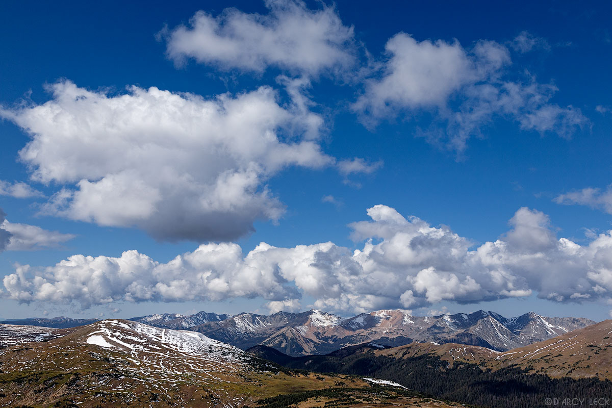 Clouds billow in blue sky above Gore Range mountains as seen from Trail Ridge, Colorado