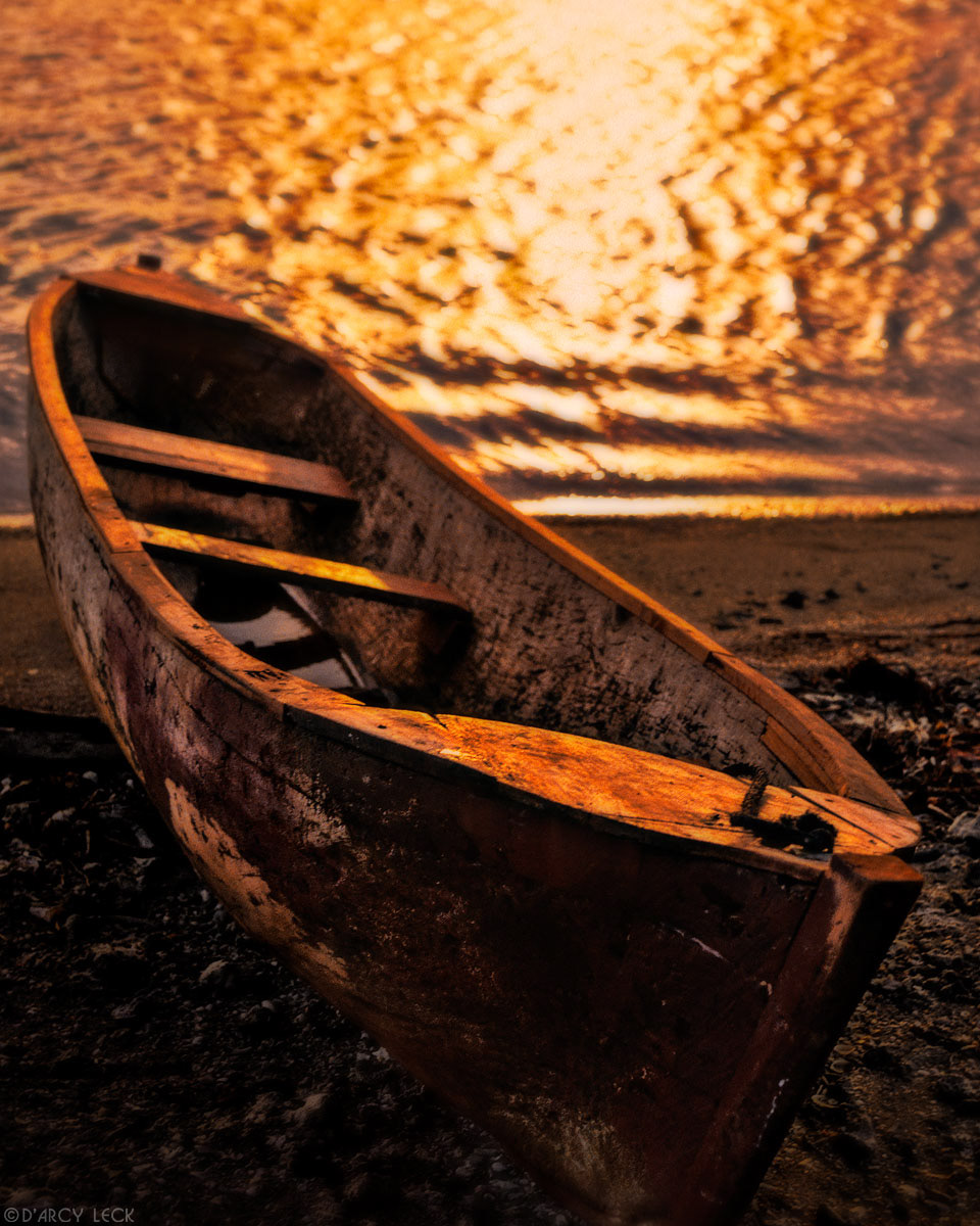 Old cayuca pulled up on beach at sunset, Roatan, Honduras