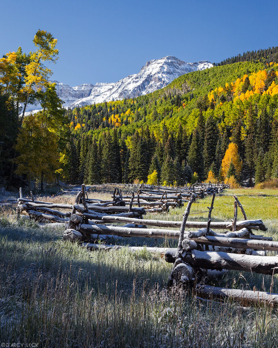 Early Autumn snow on rail fence along field with snow-capped peaks of the San Juan Mountains beyond, Colorado