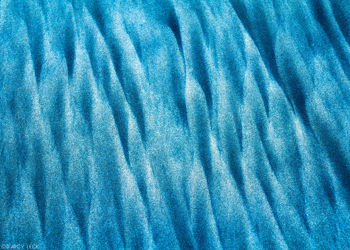 Blue and white sand streaks along beach