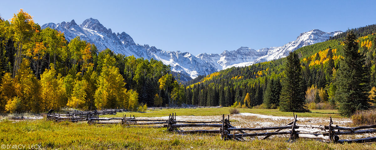 Rail fence with early Autumn snow in field with snow-capped peaks of the San Juan Mountains beyond, Colorado
