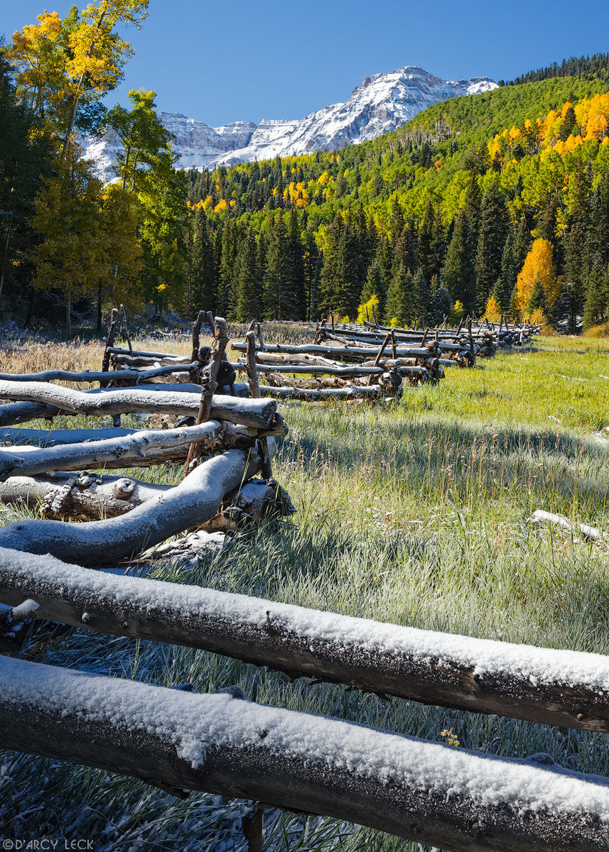 Rail fence with early Autumn snow in field with snow-capped peaks of the San Juan Mountains beyond, Colorado