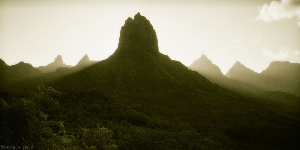 Mount Mouarou and other volcanic peaks are silhouetted against sun, Moorea, French Polynesia
