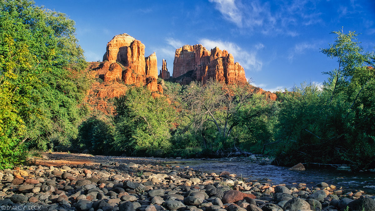 Oak Creek flows through stony river bed with the Cathedral Rocks in the distance, Arizona