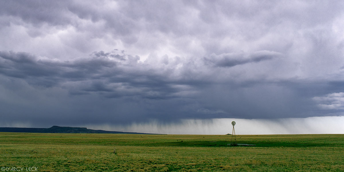 Wind pump stands in prairie rangeland before approaching rain storm in Union County, New Mexico