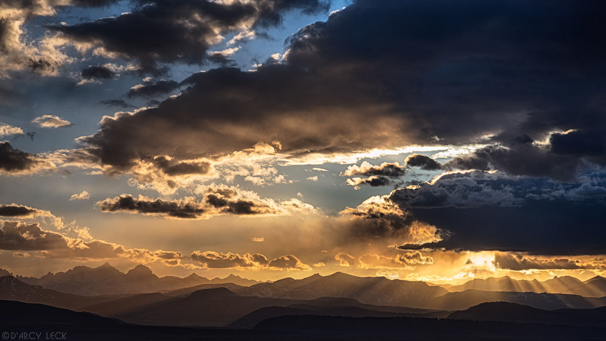 Sun rays beam through clouds at sunset over the Ritter Range of the Sierra Nevada Mountains near Mammoth Lakes, California